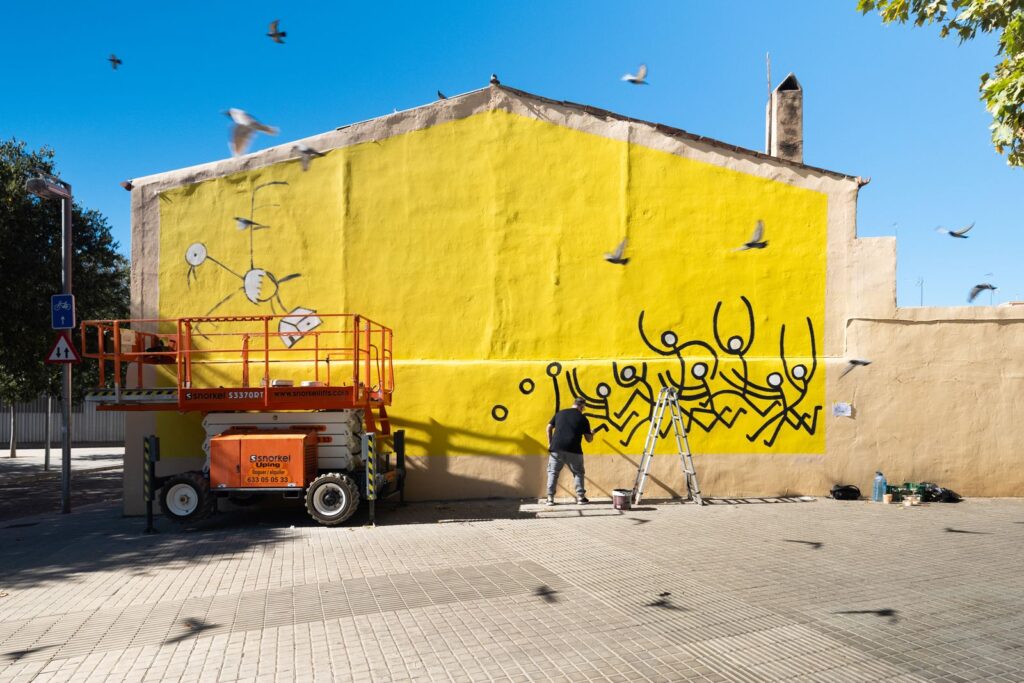 El mur del carrer Trinxant 14, que és una casa, amb els primers personatges de Javirroyo i coloms volant, mural d'art urbà CASA NOSTRA, Barcelona, Rebobinart 2026