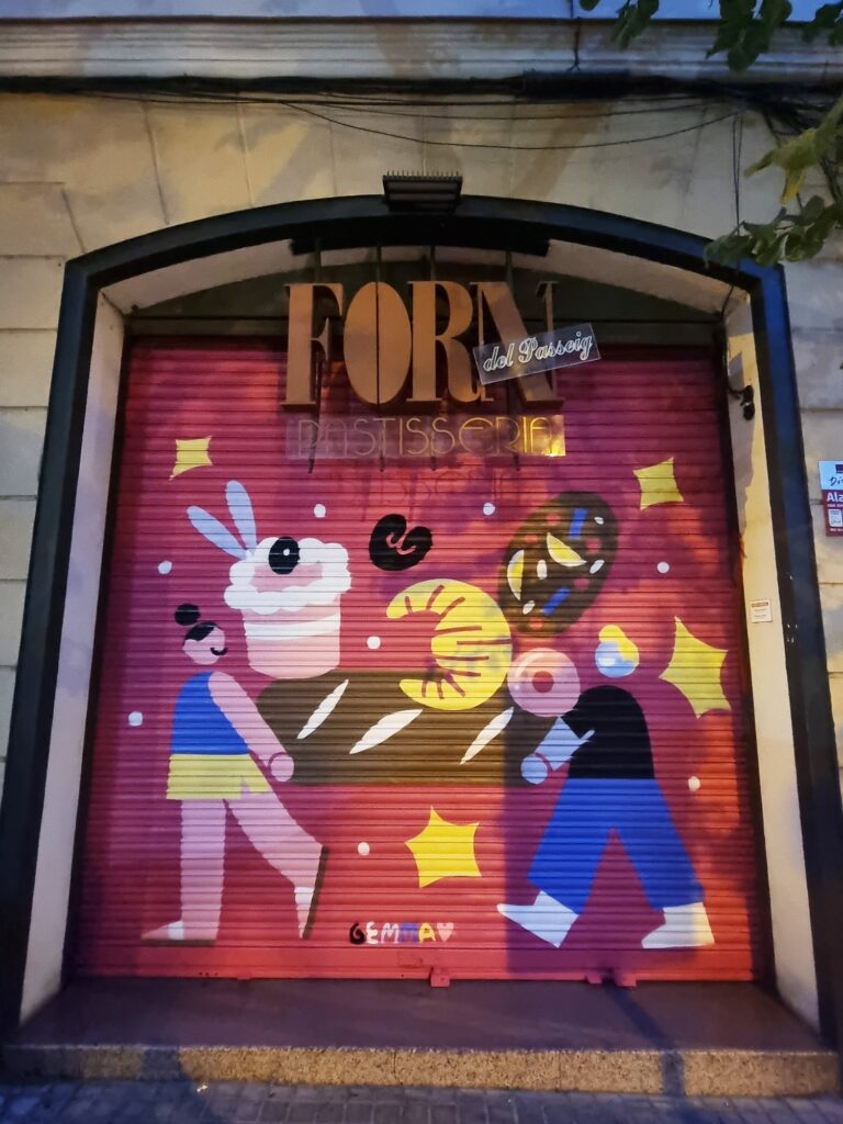 Persiana del Forn del Passeig pintada por Gemma Fontanals con dos figuras tras un mostrador lleno de croissants, lazos, berlinas y un panecillo con forma de conejo, sobre fondo rojo — Persianes que fan barri, Sant Andreu, Barcelona, Rebobinart 2026