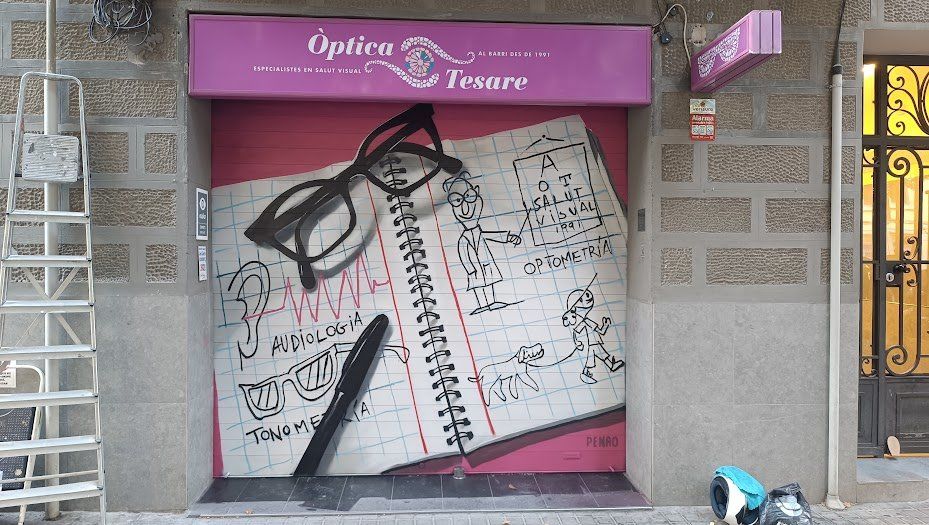 Persiana optica tesare — Penao, Les Corts Persiana de l'Òptica Tesare pintada per Penao amb unes ulleres de pasta negres i un bolígraf realistes sobre una llibreta d'espiral oberta amb una orella, un optometrista, un optotip i les paraules audiologia i optometria, sobre fons rosa — Persianes que fan barri, Les Corts, Barcelona, Rebobinart 2026