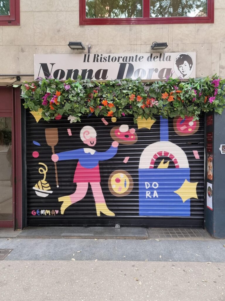Persiana del Ristorante della Nonna Dora pintada por Gemma Fontanals con una figura sirviendo pizza ante un horno de leña, un plato de espaguetis y el nombre Dora, sobre fondo negro — Persianes que fan barri, Sant Andreu, Barcelona, Rebobinart 2026