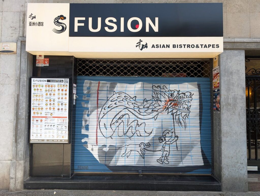 Persiana s fusion — Penao, Les Corts Persiana de S Fusion pintada per Penao amb un drac oriental que treu foc, un nen i un gos dibuixats amb línia negra sobre un full de quadern, sobre fons blau — Persianes que fan barri, Les Corts, Barcelona, Rebobinart 2026