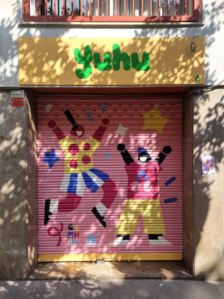 Persiana de YUHU pintada por Gemma Fontanals con dos figuras celebrando con los brazos en alto, una con vestido amarillo de lunares, sobre fondo rosa — Persianes que fan barri, Sant Andreu, Barcelona, Rebobinart 2026