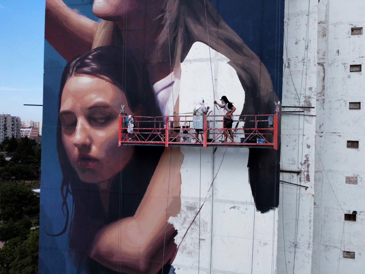 WeDo Goás pintant un mural de gran format des de la plataforma: el temps i l'ofici que demana una obra